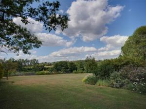 a large grass field with trees and clouds in the sky at Holiday Home Baley by Interhome in Goudhurst