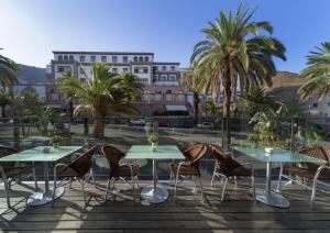 eine Terrasse mit Tischen und Stühlen und ein Gebäude in der Unterkunft Occidental Santa Cruz Contemporáneo in Santa Cruz de Tenerife