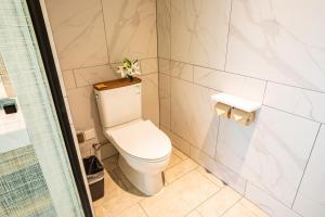 a bathroom with a toilet with a plant on top of it at Metropolo Jinjiang Weihai Railway Station in Weihai