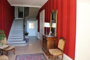 un couloir avec des murs rouges, un miroir et des chaises dans l'établissement CLOS MARIE, à Iguerande