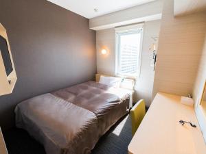 um pequeno quarto com uma cama e uma secretária em Super Hotel Tokyo JR Shinkoiwa em Tóquio