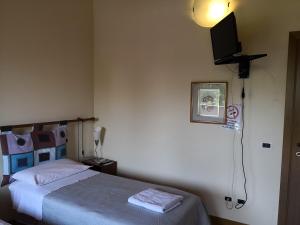 a bedroom with a bed and a tv on the wall at Trattoria Bar Oasi in Pocenia