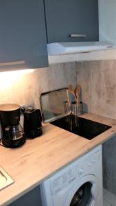 a kitchen counter with a sink and a washing machine at Appartement Carnon Plage in Carnon-Plage