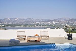 a patio with two chairs and a table and a pool at Naxian Utopia | Luxury Villas & Suites in Stelida