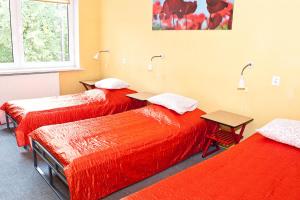 a room with two beds with red sheets and a table at Nest Nocleg Poznań in Poznań