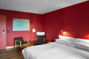 a bedroom with a red wall with a bed and a chair at Casa Camper Berlin in Berlin