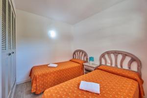two beds in a small room with orange sheets at Inter Apartments in Salou