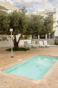 a pool in a courtyard with chairs and a tree at Oceania Bay Village in Pyla