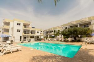 a swimming pool in front of some apartment buildings at Oceania Bay Village in Pyla