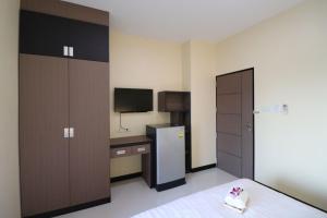 Cette chambre comprend un lit, un bureau et une télévision. dans l'établissement ตะวันอพาร์ทเม้นท์โฮเทลThawanapartmentHotel, à Satun
