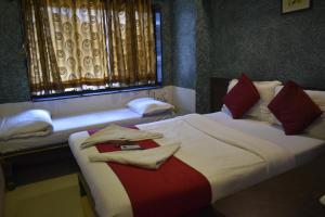 a bedroom with two beds and a window at Hotel Arma Court in Mumbai