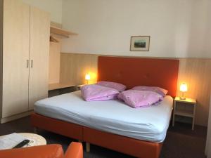 ein Schlafzimmer mit einem Bett mit lila Kissen darauf in der Unterkunft Pension Latemar in Kaltern