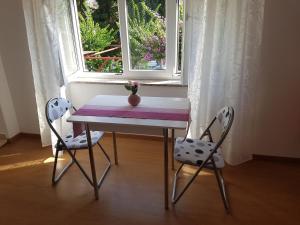 una mesa y dos sillas frente a una ventana en Apartments and Rooms Rosemari, en Mali Lošinj