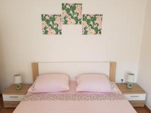 1 cama con 2 almohadas rosas y 2 cuadros en la pared en Apartments and Rooms Rosemari, en Mali Lošinj