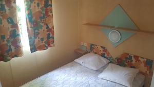 a small bedroom with a bed and a window at Camping LE PIGEONNIER in Saint-Crépin-et-Carlucet