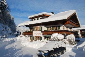 a snow covered house with a car in front of it at Haus Andrea in Fischen