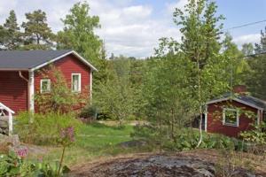 una casa roja y un patio con una casa en Stora Timrarö Unwind, en Vadholma