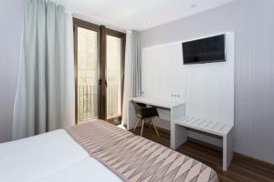a bedroom with a bed and a desk with a computer at Hostal Operaramblas in Barcelona
