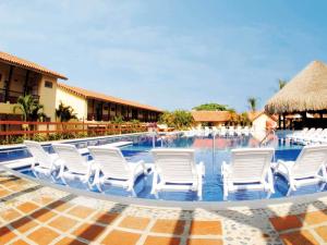 a group of white chairs in a swimming pool at Decameron Panaca - All Inclusive in Quimbaya