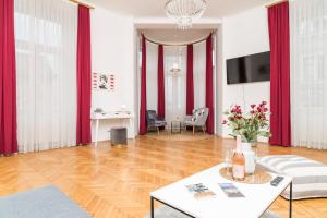 a living room with red curtains and a wooden floor at Rainer Maria Rilke Suite in Vienna