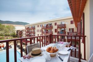 - une table avec de la nourriture sur un balcon avec vue sur un bâtiment dans l'établissement Résidence Prestige Odalys Les Canissons, à Cavalaire-sur-Mer