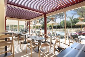 un restaurant avec des tables et des chaises ainsi qu'une piscine dans l'établissement Résidence Prestige Odalys Les Canissons, à Cavalaire-sur-Mer