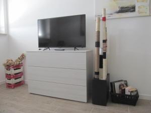 a white dresser with a tv and two cricket bats at Station Home in Sesto San Giovanni