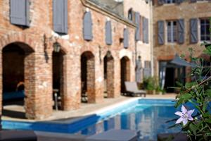 a swimming pool in front of a brick building at Maison d'Hotes Delga in Gaillac