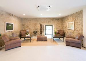 a waiting room with chairs and tables and stone walls at Reitoral de Parada in Parada del Sil