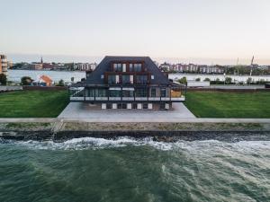 a house on the water next to a body of water at Fliegerdeich Hotel & Restaurant in Wilhelmshaven