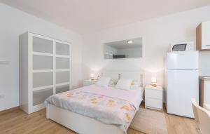 Habitación blanca con cama y nevera. en Apartment Complex Jelena, en Funtana