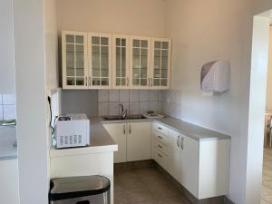 una pequeña cocina con armarios blancos y fregadero en Hlín Guesthouse, en Varmahlid