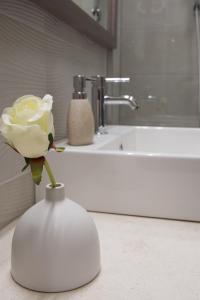 a white flower in a vase in front of a sink at Omia in Belgrade