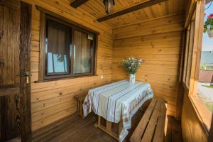 a wooden cabin with a table with a vase of flowers at ROXENA APART in Szack