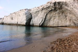 a rock wall next to a beach with the water at Galini in Agia Irini Milos