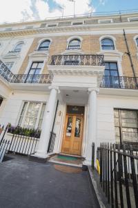 a large white building with a wooden door at New Kent Apartments in London