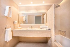 
a bathroom with a tub, sink and mirror at Horizon Beach Resort in Mastihari
