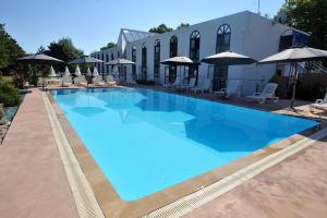 uma grande piscina azul com cadeiras e guarda-sóis em Agape Hotel Niort- Bessines em Bessines