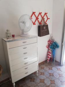 a white dresser with a fan on top of it at Case Nausica in Marina di Ragusa