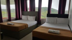 two beds in a hotel room with windows at Vagamon Clouds in Vagamon