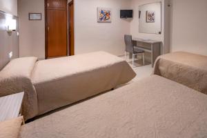 a hotel room with two beds and a desk at Hotel Niza in Salou