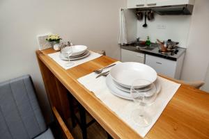 a wooden table with two plates and glasses on it at Žižkov Cosy Studio Apartments in Prague