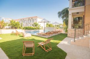 a yard with chairs and a swimming pool and a building at Perla Luxury Living in Parga