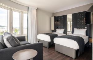 a hotel room with two beds and a couch at Point A Hotel Edinburgh Haymarket in Edinburgh