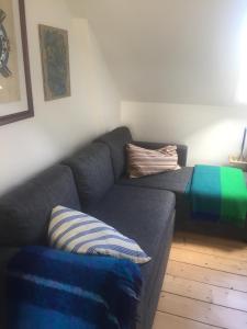 a living room with a gray couch with a striped pillow at Jette’s værelsesudlejning in Rudkøbing