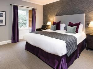 a large bedroom with a large bed with purple pillows at Craigatin House & Courtyard in Pitlochry