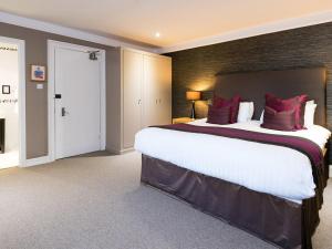 una grande camera da letto con un grande letto con cuscini rossi di Craigatin House & Courtyard a Pitlochry