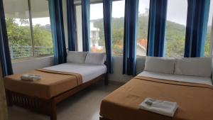 two beds in a room with large windows at Vagamon Clouds in Vagamon