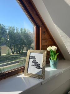 a window sill with a picture and a vase of flowers at Gem in Győr - free parking in Győr