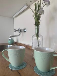 two cups on a table with a vase with flowers at Gem in Győr - free parking in Győr